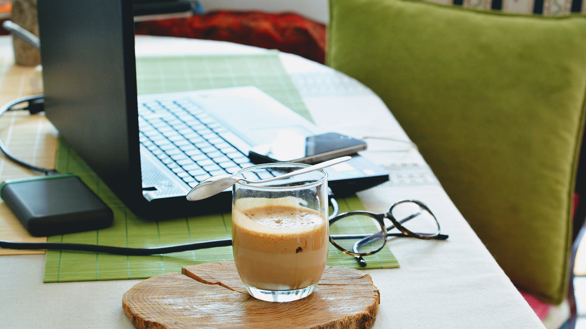 Desk with laptop, iced coffee, and glasses