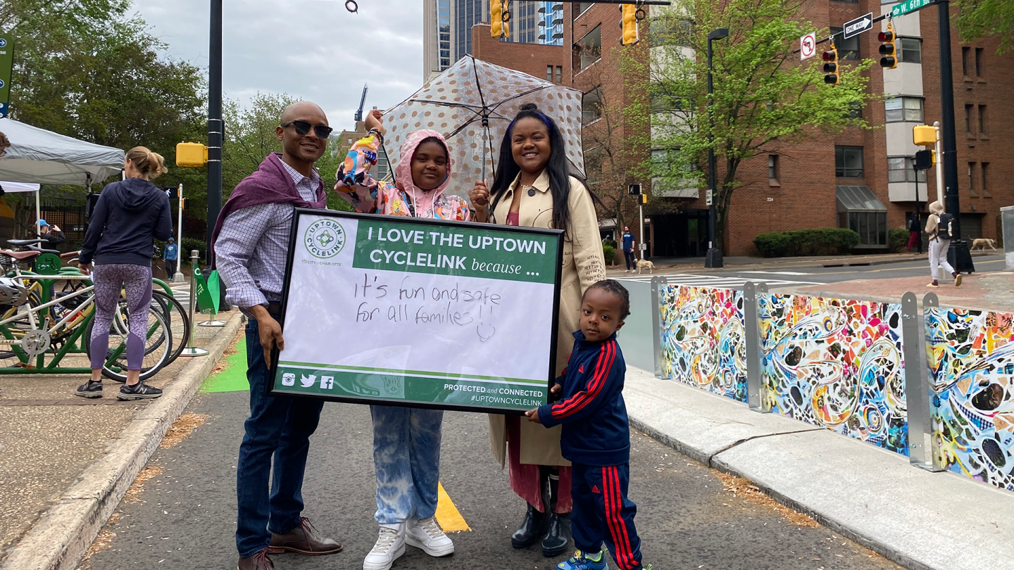 Family holding sign about why they love the Uptown Cycle Link