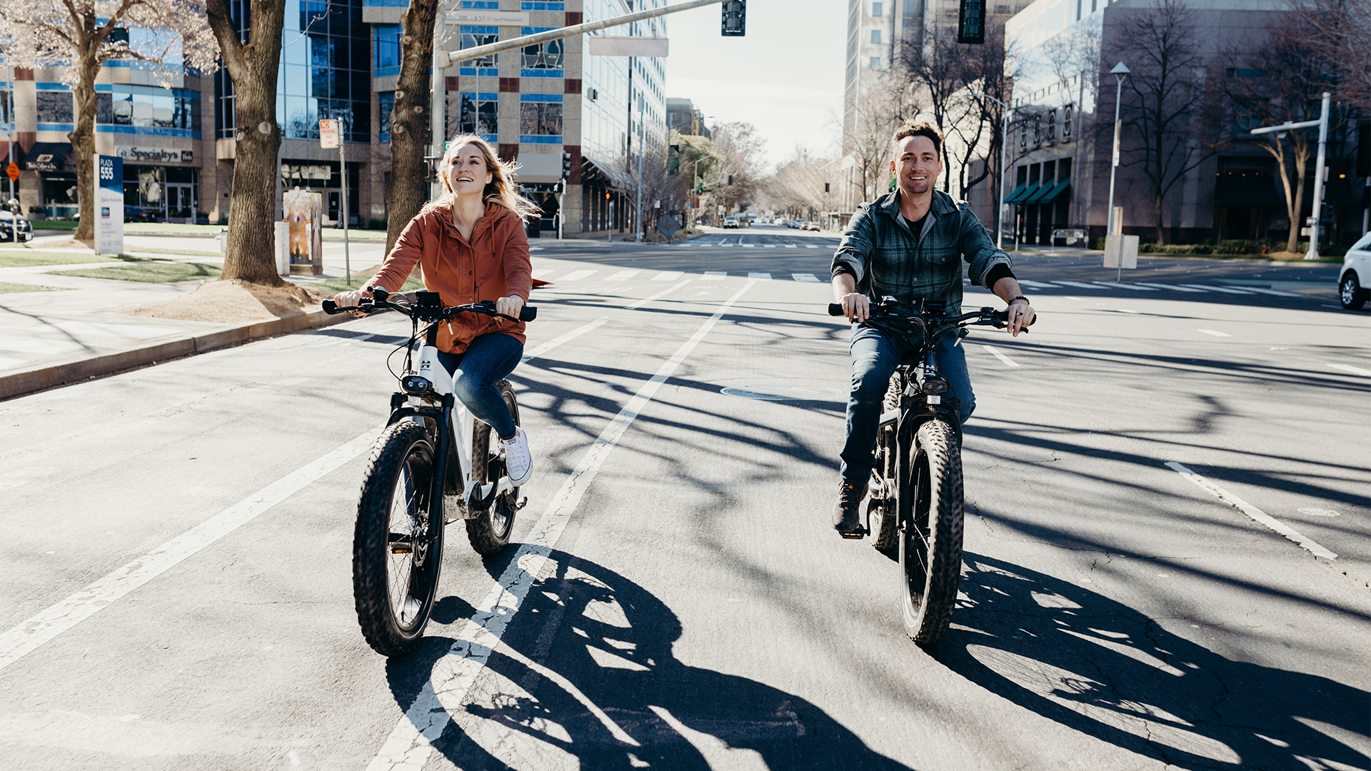 Two people riding bikes down a city street