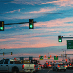 Cars waiting at traffic signals with sunset in background