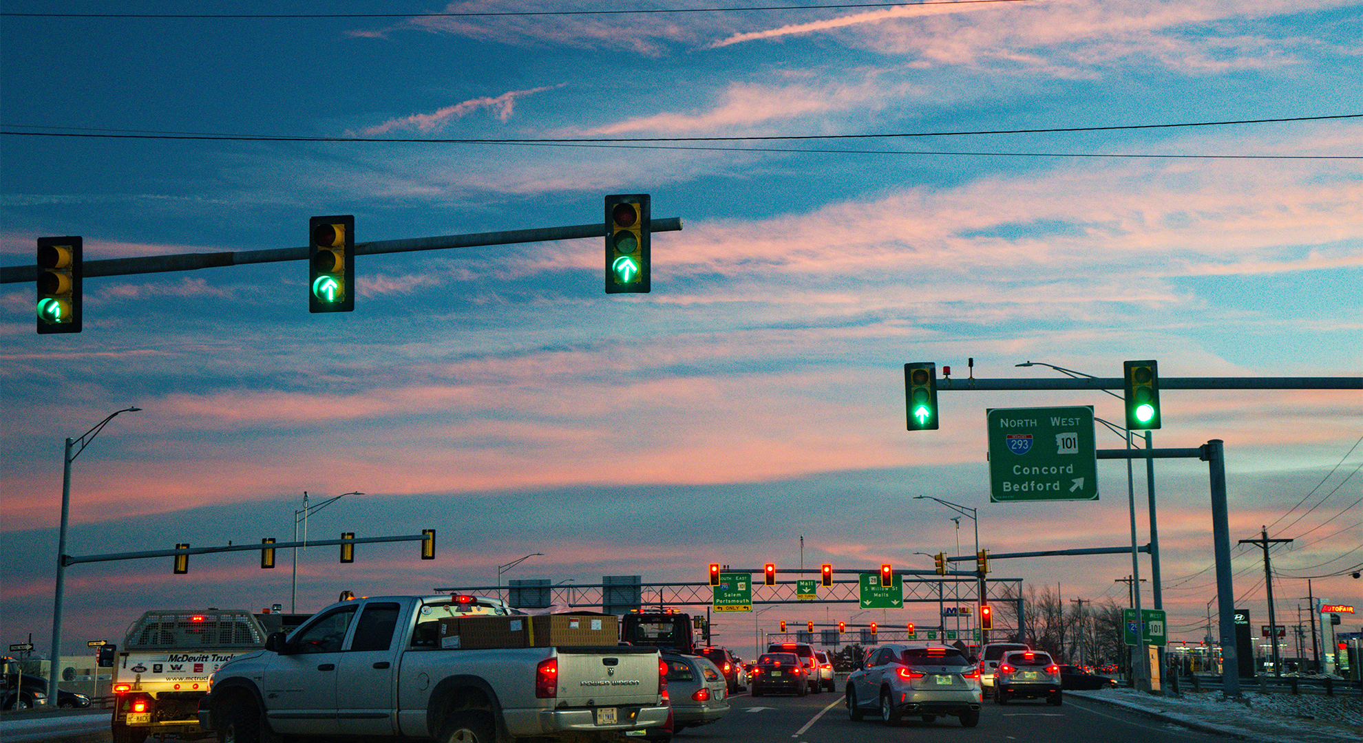 Cars waiting at traffic signals with sunset in background