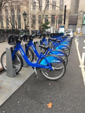 Row of blue CitiBikes on street.