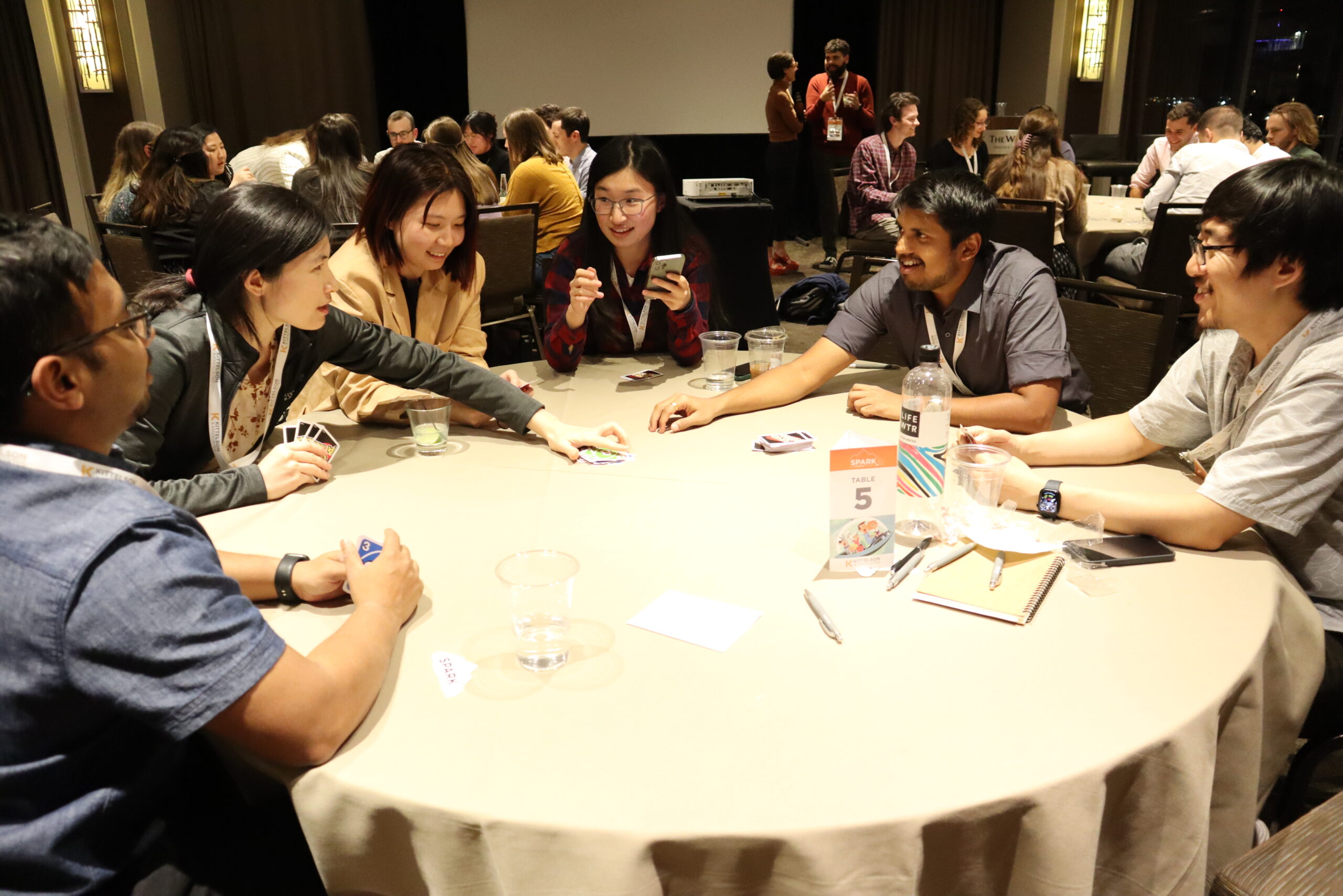 Group of people sitting at a circular table playing Uno.