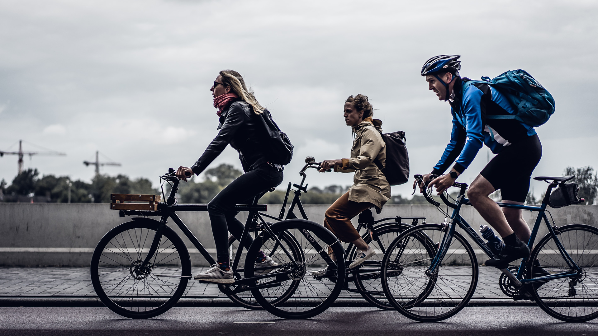 3 bikers biking next to each other on a road.