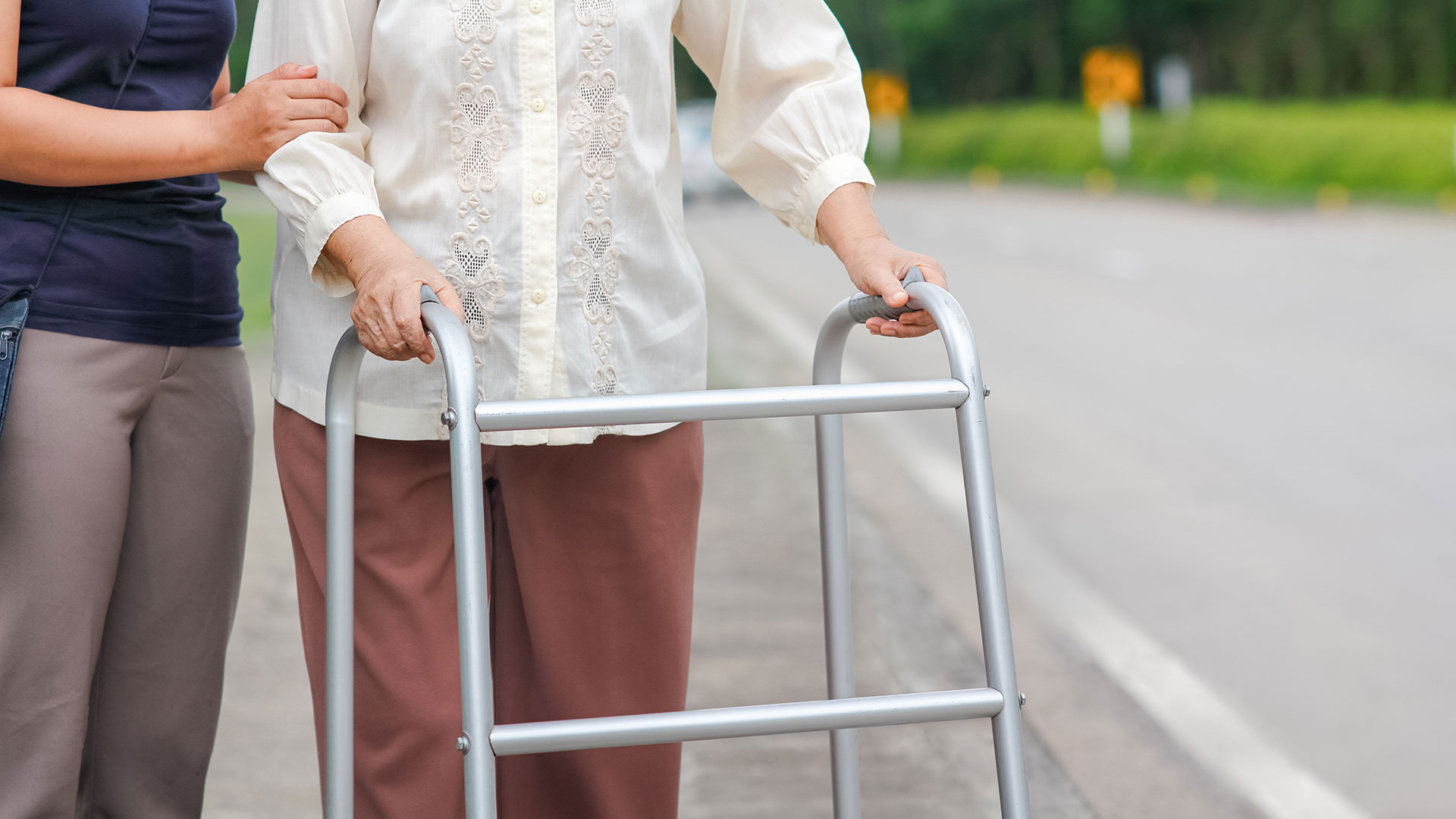 Person walking on sidewalk using walker