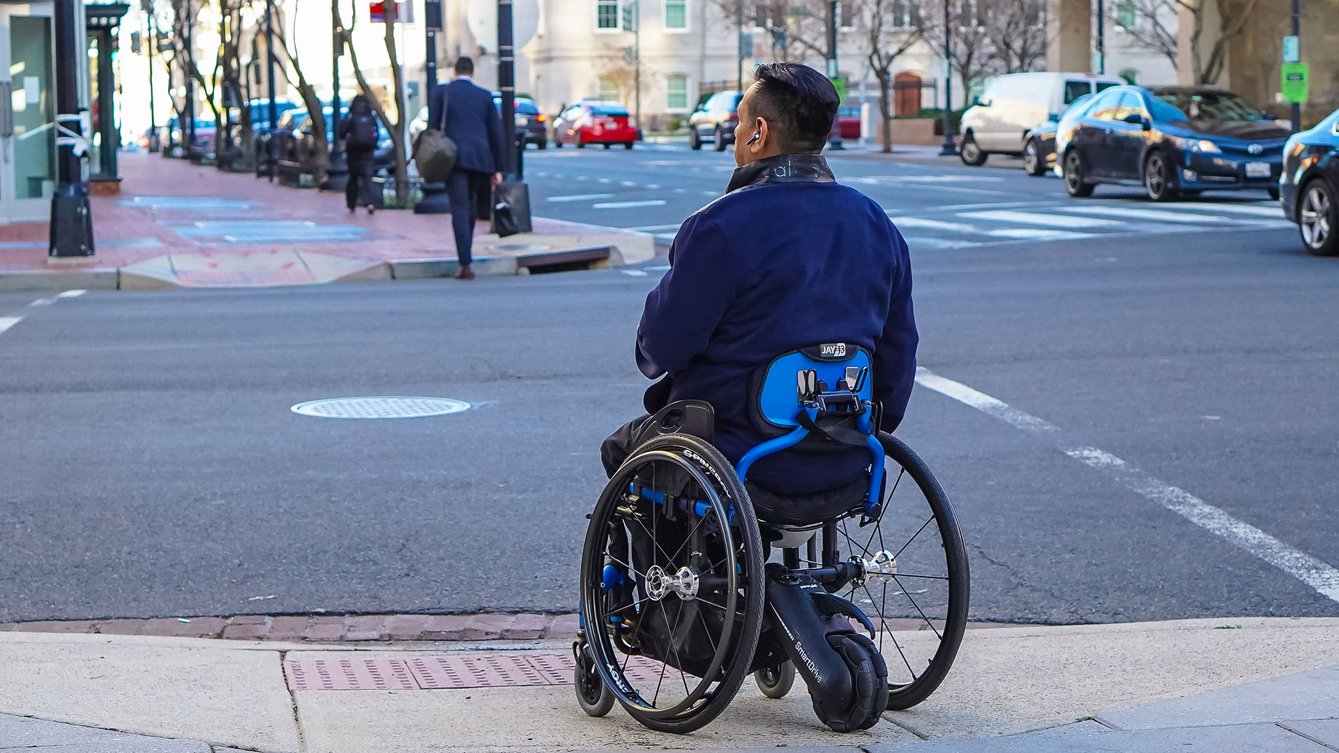 Man sitting in wheelchair waiting to cross street