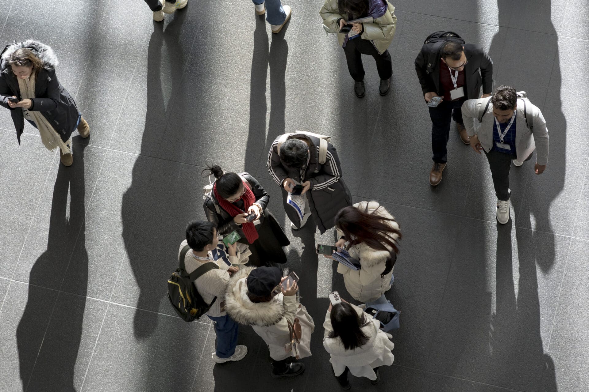 Above-view of a group of TRB attendees standing in a circle checking their phones.