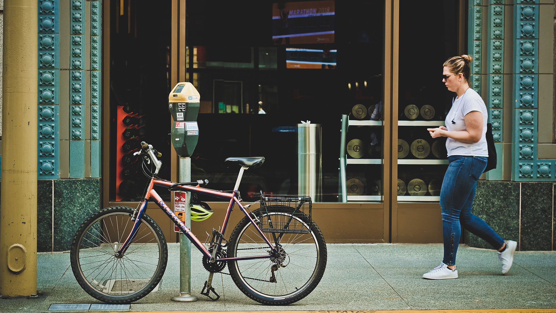 Picture of a bike on a sidewalk downtown and person walking by