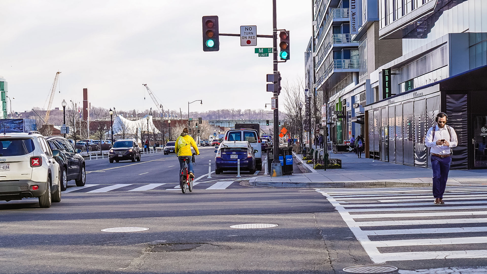 Person walking, person biking, and cars driving down a downtown street in Washington, D.C.