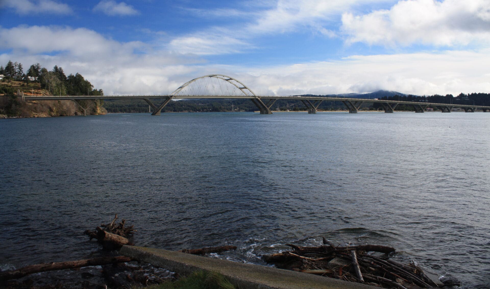 A bridge spans the shore of Alsea Bay on the Oregon Coast. It's a clear day and the water is calm.