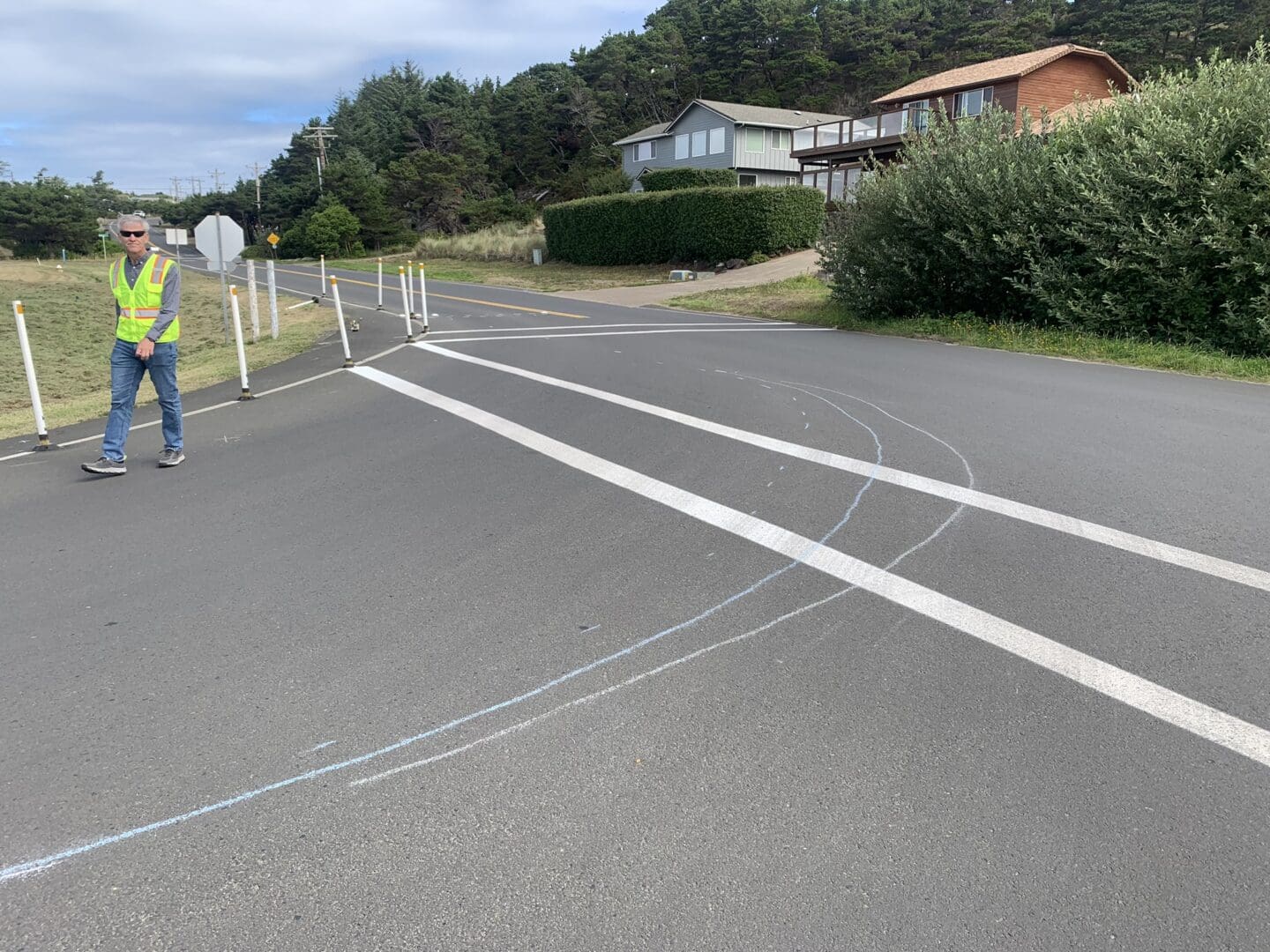 A traffic engineer in a high-visibility vest walks along the roadway at an intersection with a tight turn.