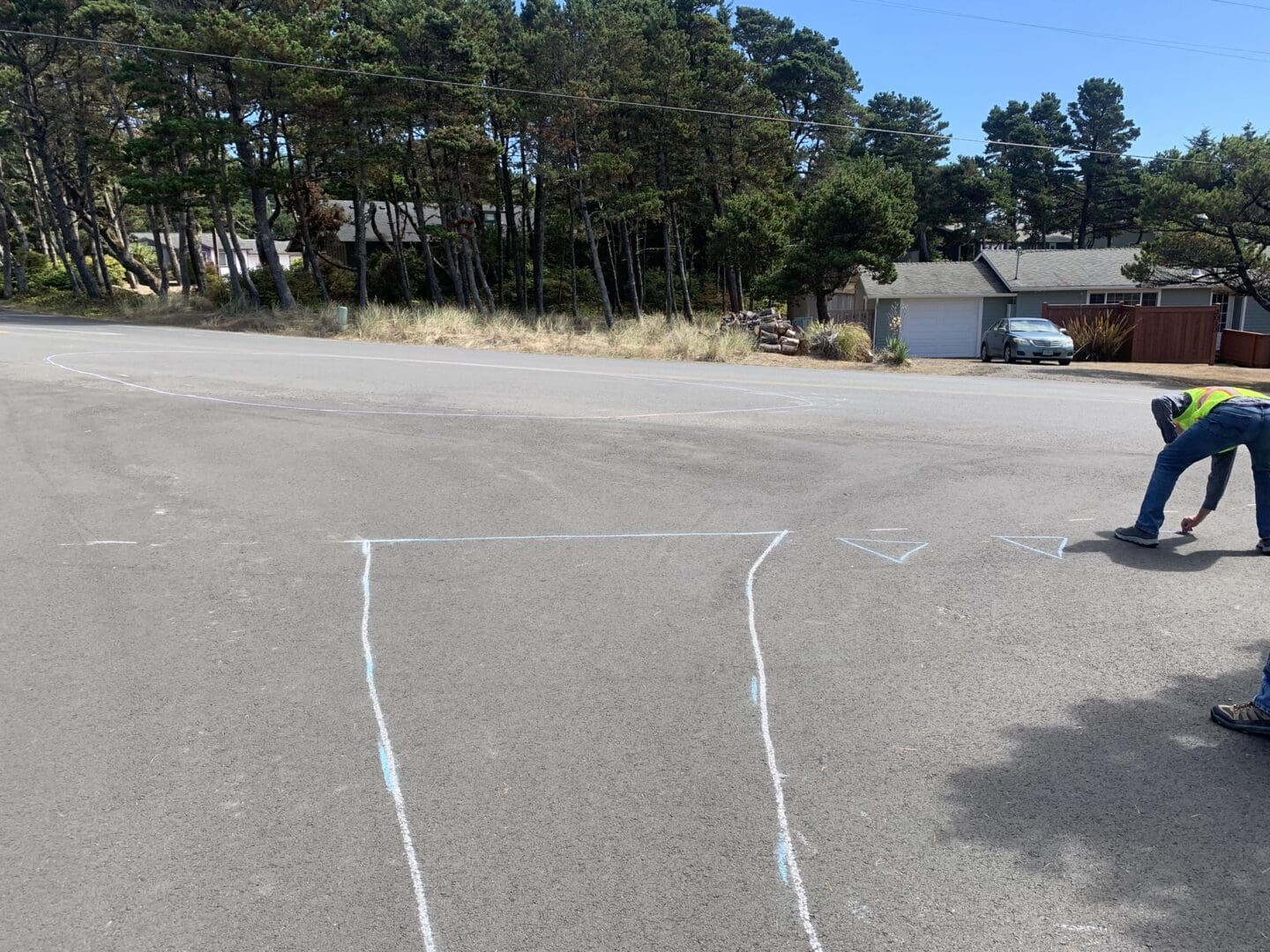 A traffic engineer in a high-visibility vest draws a new intersection configuration on the roadway with chalk.