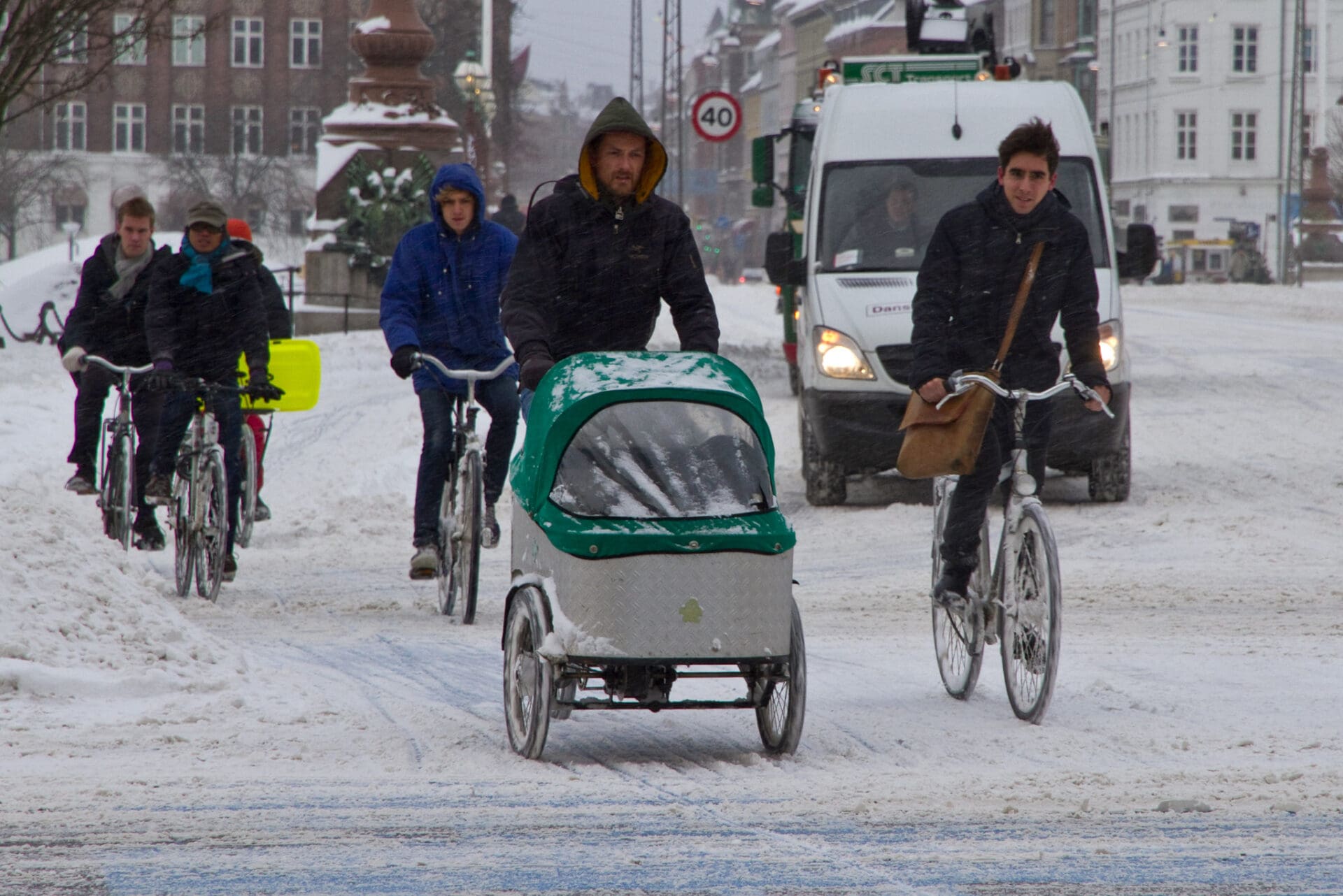 People riding bicycles and a cart in the snow