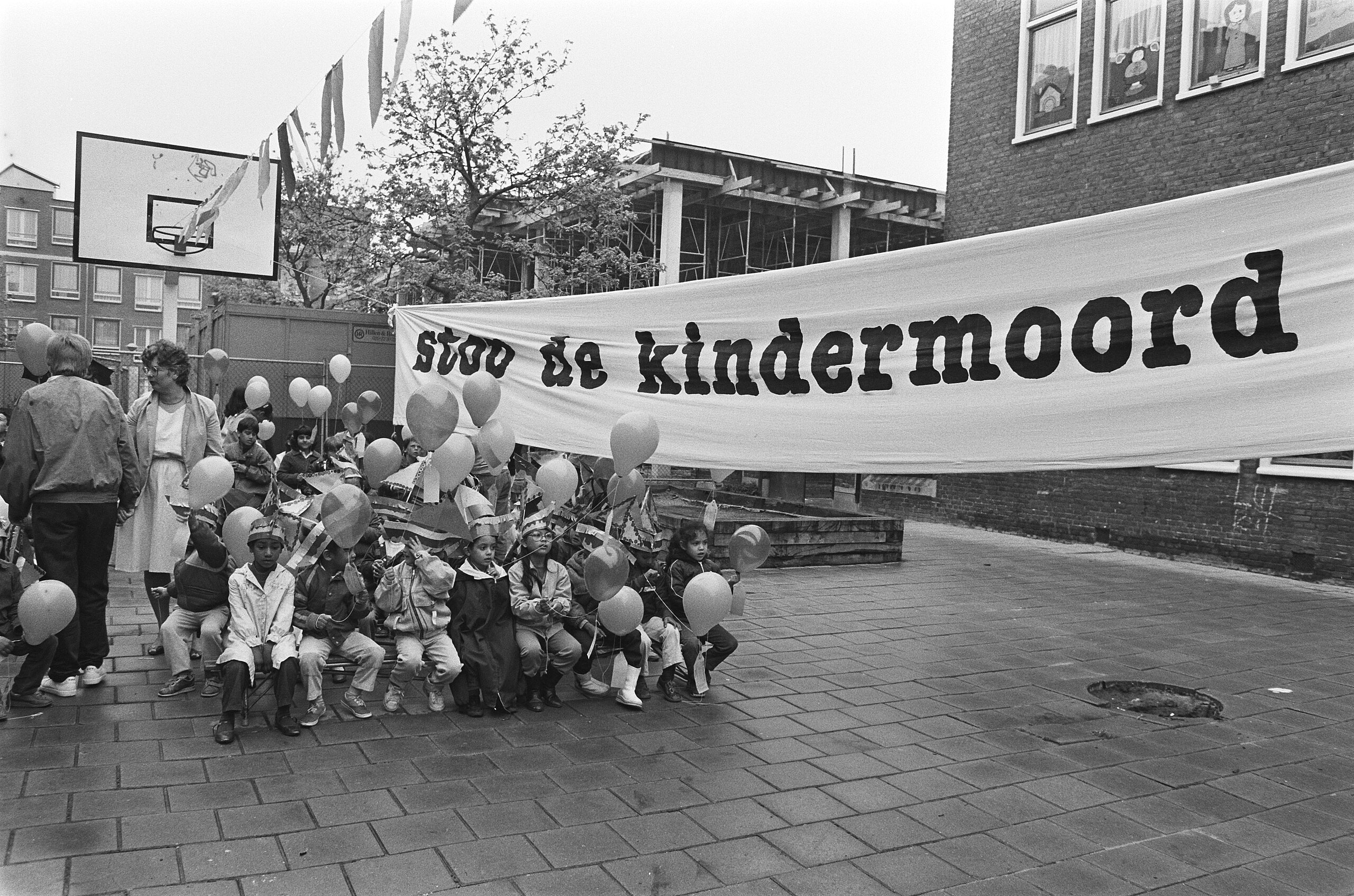 A group of people holding a banner that says "stop de kindermoord."