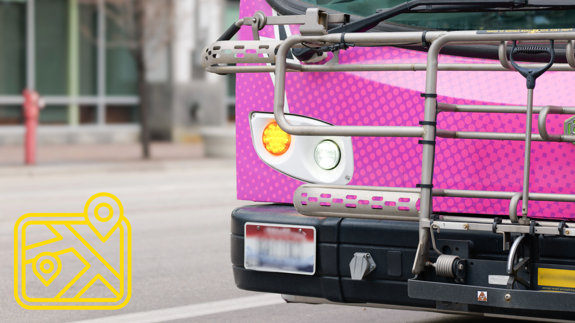 Photograph showing close-up of front section of pink city bus with illuminated right turn signal and bike rack. Background includes blurred urban street.