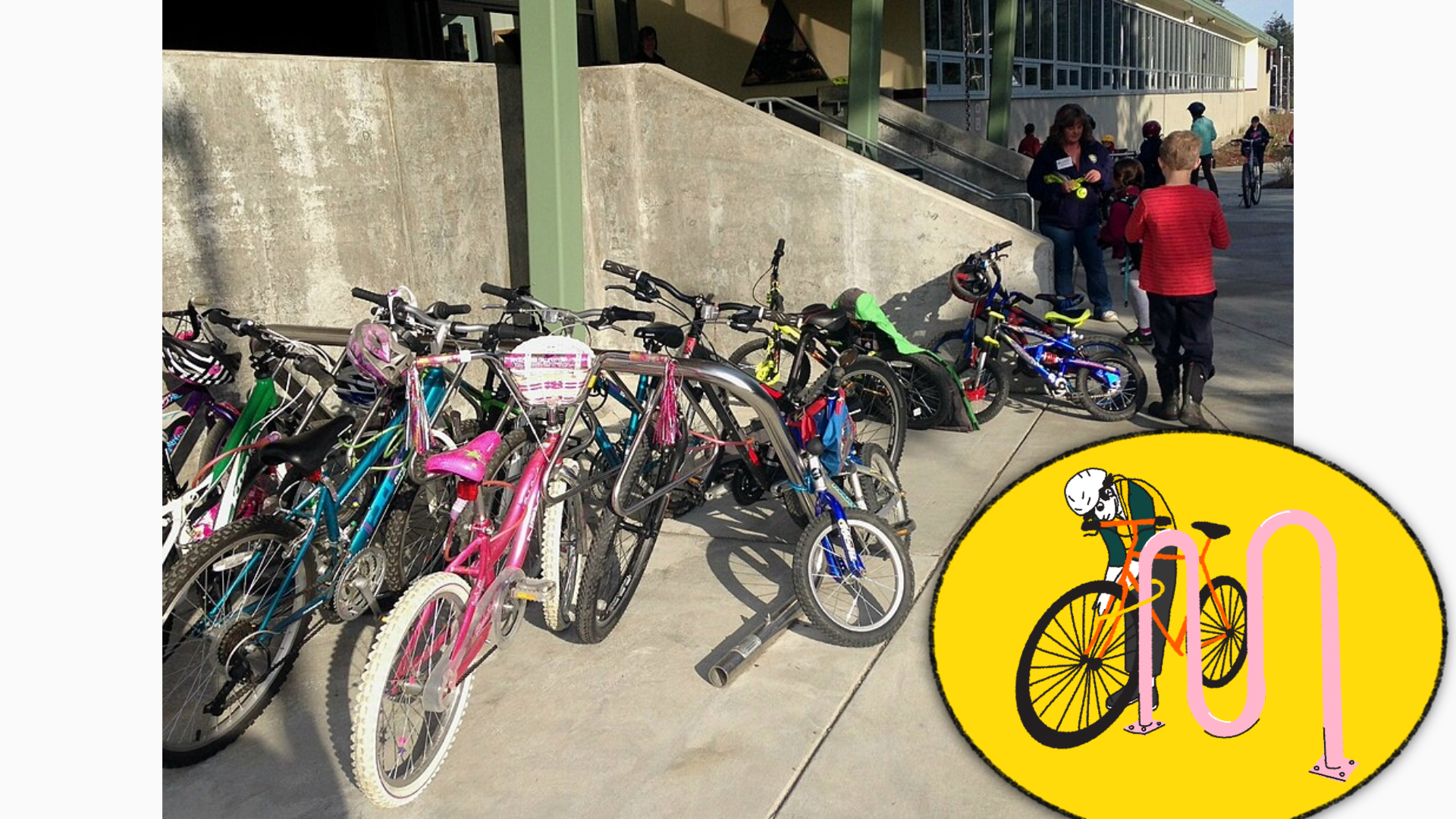 A photo of many bicycles parked outside the entrance to a school.