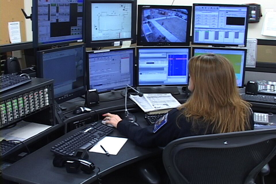 Photograph of a 911 control-room operator monitoring multiple computer screens.